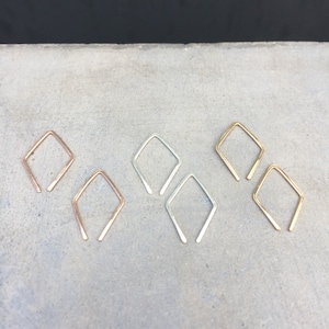 May include: Three pairs of diamond-shaped earrings in gold, silver, and rose gold.