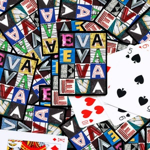 May include: A close-up of a pile of playing cards with a variety of designs. The cards are arranged in a random order, and some of them are face up. The cards are all standard playing cards, with the exception of one card that has a unique design. The unique card has the word "EVA" repeated multiple times in a colorful, geometric pattern.