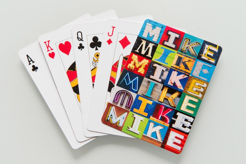 May include: A set of five playing cards, including the Ace of Clubs, King of Hearts, Queen of Clubs, Jack of Diamonds, and a card with the word "MIKE" spelled out in colorful letters.