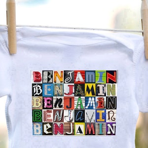 May include: White baby onesie featuring a colourful graphic of the name "Benjamin" spelled out in various fonts and colours.