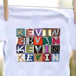 May include: White baby onesie with the name "Kevin" spelled out in colorful letters. Each letter is made up of a different image of a sign with the letter on it.