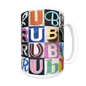 May include: White ceramic mug with a colorful design of the word "RUBY" spelled out in different fonts and colors. The letters are arranged in a grid pattern.