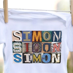 Puede incluir: Un body blanco para bebé con un collage colorido de letras que deletrean el nombre "SIMON".