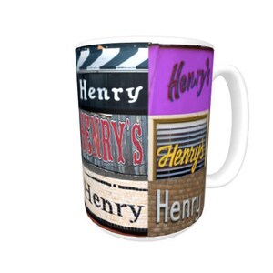 Op de afbeelding: Witte keramische mok met een kleurrijke collage van de naam "Henry" in verschillende lettertypen en stijlen. De mok heeft een zwart handvat.