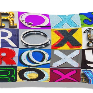 May include: A pillow with a colorful design featuring the word "ROXY" spelled out in different fonts and colors. Each letter is made up of a different design, including circles, crosses, and neon lights.
