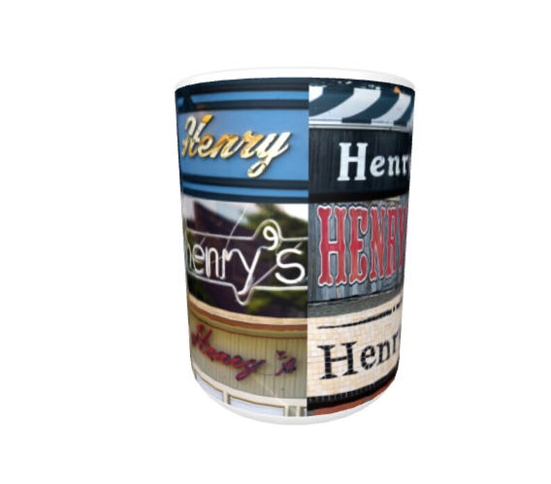 Op de afbeelding: Witte keramische mok met een collage van kleurrijke borden met de naam "Henry's" in verschillende lettertypen en stijlen.