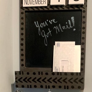 May include: A wooden wall organizer with a chalkboard, calendar, and key hooks. The chalkboard reads "You've got Mail!" and displays the date as Friday, November 19. Keys hang below.