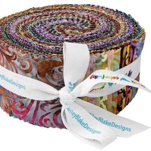 Puede incluir: Un rollo de tiras de tela coloridas, atado con una cinta blanca. La tela muestra una variedad de patrones y colores, incluyendo azules, morados y naranjas. La cinta lleva impreso el texto "Riley Blake Designs" y "colorfully".