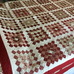 Puede incluir: Un edred&oacute;n hecho a mano con un patr&oacute;n repetido de cuadrados rojos y crema. El edred&oacute;n presenta un patr&oacute;n de diamantes con un fondo blanco y un borde rojo. El edred&oacute;n est&aacute; hecho de tela y probablemente se usa para ropa de cama.