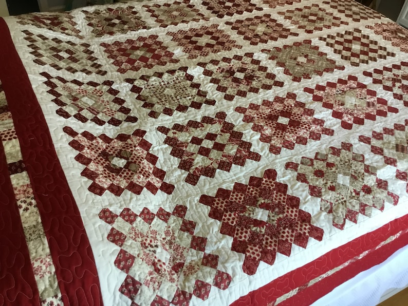 Puede incluir: Un edred&oacute;n hecho a mano con un patr&oacute;n repetido de cuadrados rojos y crema. El edred&oacute;n presenta un patr&oacute;n de diamantes con un fondo blanco y un borde rojo. El edred&oacute;n est&aacute; hecho de tela y probablemente se usa para ropa de cama.