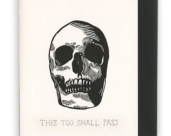 May include: Black and white illustration of a skull with the text "This too shall pass" below it.