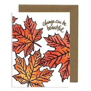 May include: Greeting card featuring orange and yellow maple leaves with black outlines. The words "change can be beautiful" are written in gold script. The card has a white front and a brown envelope.