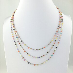 May include: A multi-strand necklace with small, colorful gemstone beads. The necklace is made of silver and features a variety of colors, including red, orange, yellow, green, blue, purple, and pink.