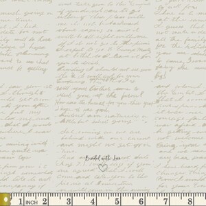 May include: Cream-colored fabric with handwritten script in a light brown hue. The text is overlaid on the fabric, with a ruler at the bottom showing measurements in inches. The words "Binded with Lovest" are visible.