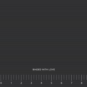 May include: A close-up of a dark gray fabric with horizontal lines. The text "BOUNDED WITH LOVE" is printed in white. A ruler is at the bottom of the image, with measurements in inches.
