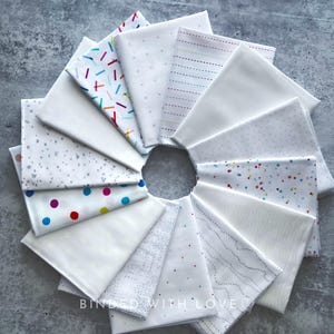 May include: A circular arrangement of folded white fabric squares, some with colorful patterns like sprinkles, dots, and dashes. The fabrics are arranged around a central opening, creating a visually appealing display. The text "BOUND WITH LOVE" is visible at the bottom.