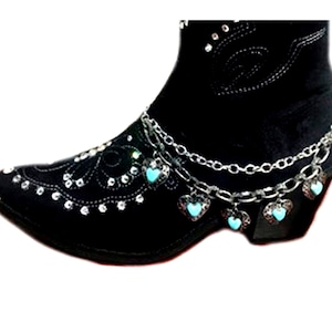 May include: Black ankle boot with silver chain and turquoise heart charms. The boot features decorative rhinestone accents and a pointed toe. The chain dangles from the boot's ankle area, adding a touch of sparkle and charm.