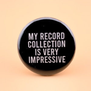 May include: A black button with white text that reads "My record collection is very impressive."