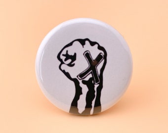 May include: A white button with a black silhouette of a fist with a large black X over it.