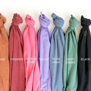 May include: Seven folded t-shirts in different colors: yam, crimson, crunch berry, violet, blue jean, light green, and black.