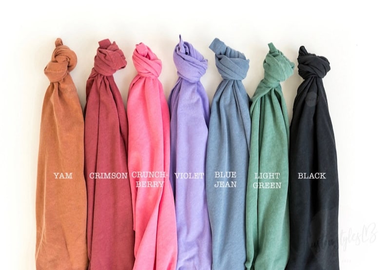 May include: Seven folded t-shirts in different colors: yam, crimson, crunch berry, violet, blue jean, light green, and black.