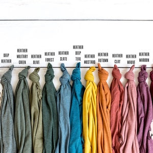 Pode incluir: Uma variedade de 15 t-shirts de diferentes cores, incluindo p&oacute; de heather, heather profundo, heather verde militar, heather oliva, heather floresta, heather ard&oacute;sia, teal profundo, heather mostarda, heather outono, heather argila, heather malva, heather vinho e heather cardeal.