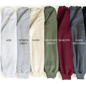 May include: A row of ten sweatshirts in different colours, including white, ash, sports grey, sand, military green, maroon, dark heather, and black.
