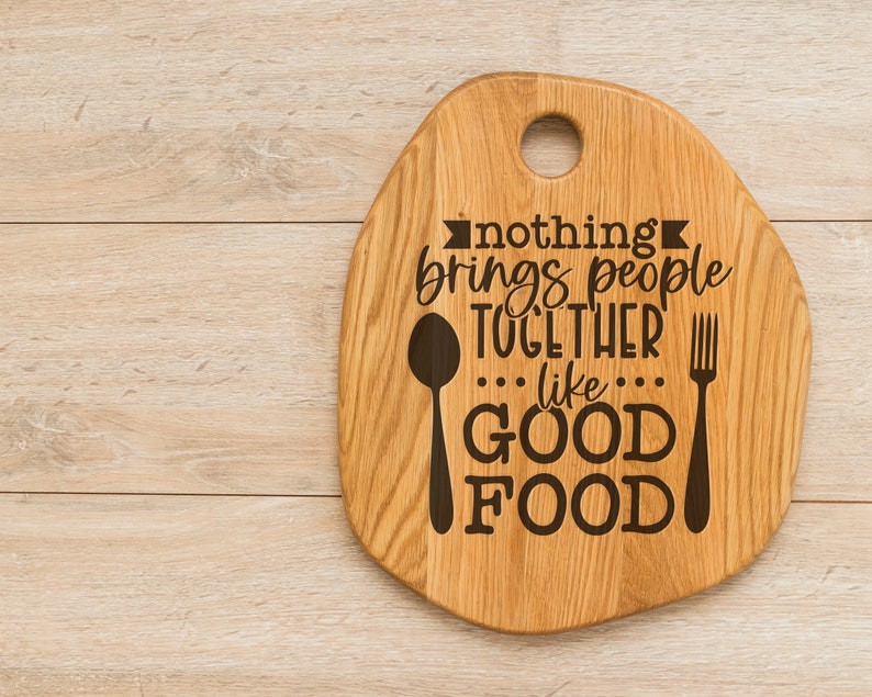 K&ouml;nnte beinhalten: Ein Schneidebrett aus Holz mit einem Griff und dem eingravierten Text "nothing brings people together like good food". Ein L&ouml;ffel und eine Gabel sind ebenfalls auf das Brett graviert.
