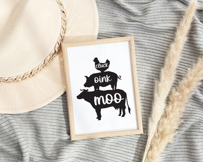 May include: A framed print with a black and white illustration of a chicken, pig, and cow stacked on top of each other. The text "cluck oink moo" is written below the animals.