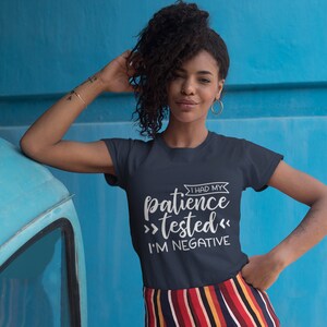 Puede incluir: Una camiseta azul marino con texto blanco que dice "Tuve mi paciencia >probada< Soy negativa".