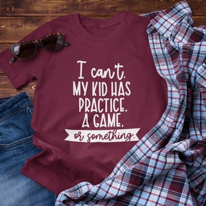 Pode incluir: Camiseta vinho com texto branco que diz "N&atilde;o posso. Meu filho tem treino, um jogo ou algo assim."