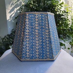 May include: A blue and beige lampshade with a geometric pattern of leaves. The lampshade is octagonal and has a beige trim.