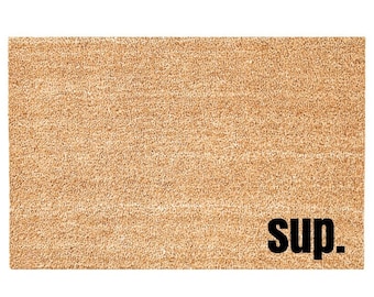May include: A brown coir doormat with the word "sup." printed in black.