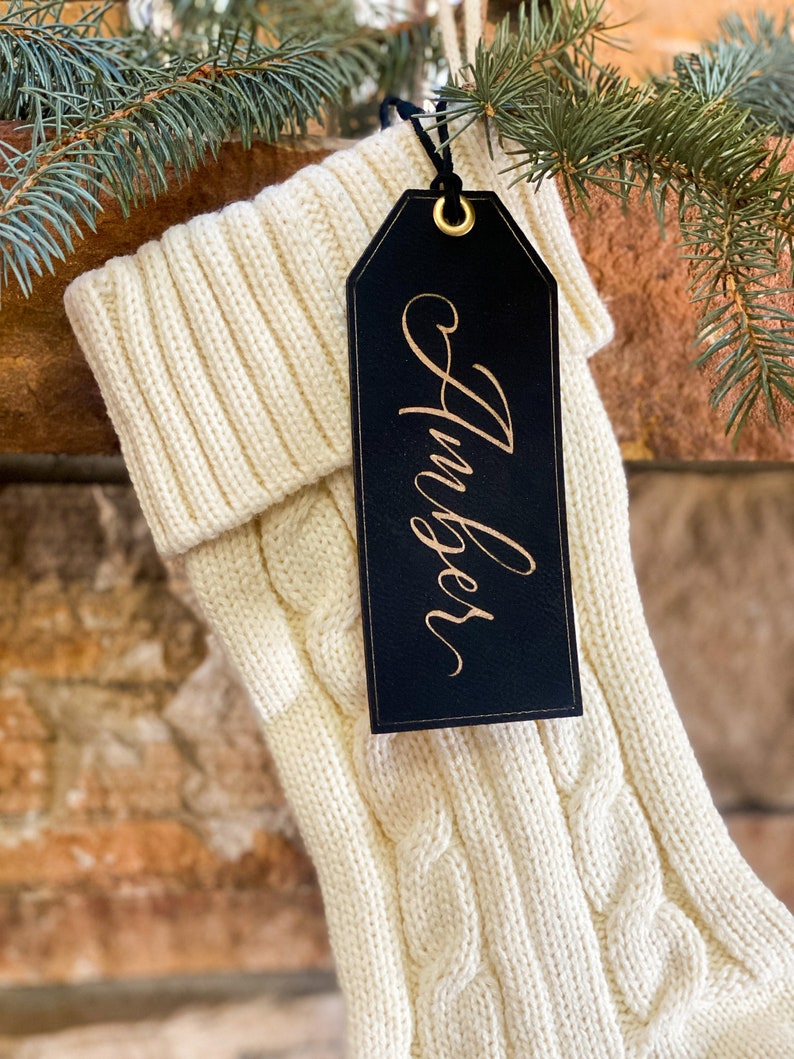 May include: A white knitted stocking with a black leather gift tag that says "Amber" in gold lettering.
