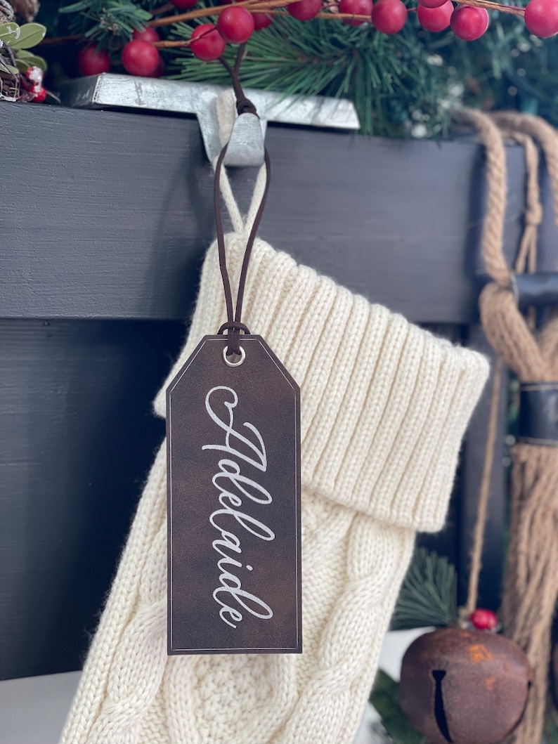 May include: A brown leather stocking tag with the name "Adelaide" written in white script.