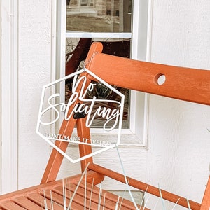 May include: White hexagon-shaped sign with the text "No Soliciting Don't Make It Weird" hanging on a wooden chair.