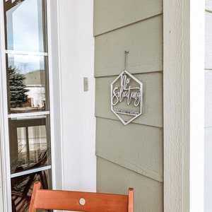 May include: A silver metal sign with the text "No Soliciting" and "Just Make It Weird" hanging on a light green wooden door. A wooden chair is in the foreground.