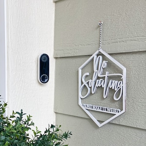 May include: White wooden sign with the text "No Soliciting Don't Make It Weird" hanging on a light green wall.