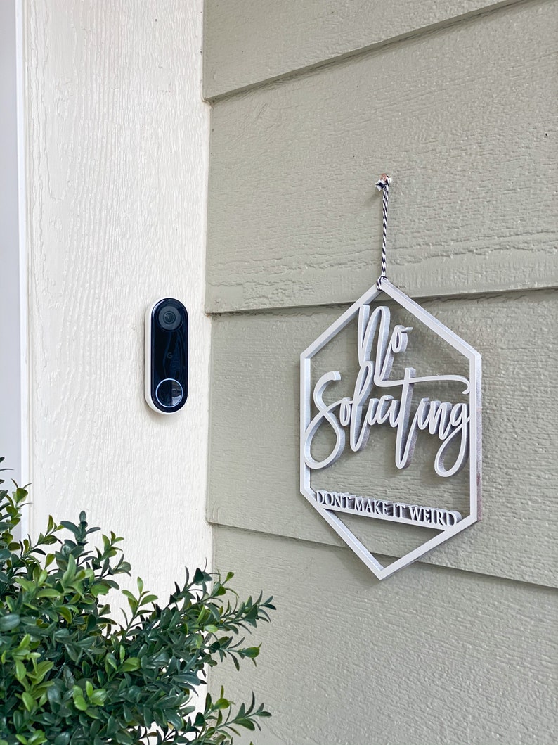 May include: White wooden sign with the text "No Soliciting Don't Make It Weird" hanging on a light green wall.