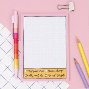 May include: Pink notepad with a dotted grid and a black border. The notepad has a checklist with the following options: very good ideas, brain dump, really must do, do not forget.