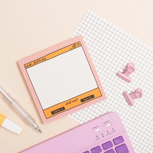 May include: A pink notepad with a computer window design. The notepad has the text "brain_dump.doc" and buttons that say "Save", "what now?" and "bin x". The notepad is on top of a sheet of graph paper with two pink paper clips.