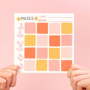 May include: A white bingo card with a pink and orange colour scheme. The card has the words "# to do list bingo" written on the left side and "PRIZES" and "LINE BINGO!" written at the top.