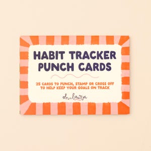May include: A rectangular pack of habit tracker punch cards with a cream center and a border of alternating orange and pink stripes. The text reads: HABIT TRACKER PUNCH CARDS, 25 CARDS TO PUNCH, STAMP OR CROSS OFF TO HELP KEEP YOUR GOALS ON TRACK, oh, laura.