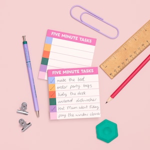 May include: Two square sticky note pads labelled FIVE MINUTE TASKS with coloured rows, a lavender mechanical pencil, two silver binder clips, a large lavender paper clip, a wooden ruler showing cm, a red pencil, and a teal hexagonal eraser.