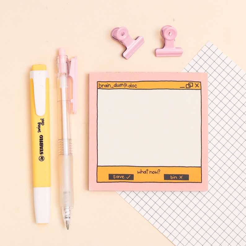 May include: Pink notepad with a drawn computer window on it. The window is titled "brain_dump.doc" and has buttons that say "Save", "what now?" and "bin". There are two yellow highlighters and a clear pen next to the notepad.