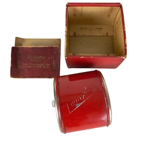 May include: Vintage red Twinplex Strop set with a red box and a small red box. The Twinplex Strop is a cylindrical shape with a silver metal rim. The small box has text that reads "Twinplex Strop".