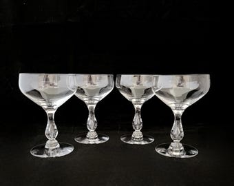 May include: Four clear glass champagne coupes with a teardrop-shaped stem.