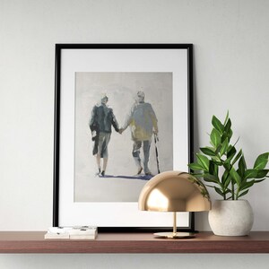 May include: Framed art print depicting two figures holding hands, walking away. The painting features muted tones of gray, blue, and yellow. The artwork is displayed on a dark brown shelf, alongside a gold lamp and a potted plant.