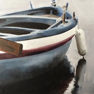 Puede incluir: Pintura al &oacute;leo de un peque&ntilde;o barco con detalles en azul, blanco y rojo. El barco est&aacute; parcialmente sumergido en el agua, con un reflejo visible. Un remo de madera descansa dentro del barco. Una boya blanca cuelga a un lado.
