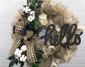 May include: A black and brown checked wreath with a black "hello" sign, white cotton bolls, and green leaves.